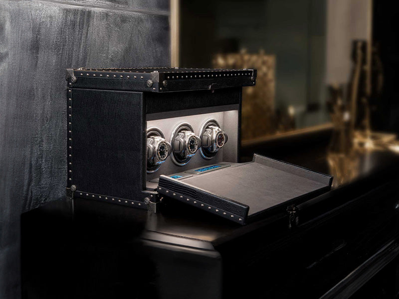 Luxury watch case with three watches on a dark surface
