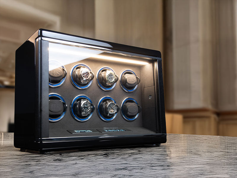 Watch winder with six rotating watch cases on a marble surface.